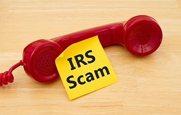 Red phone next to small paper note with the text "IRS Scam" written on it