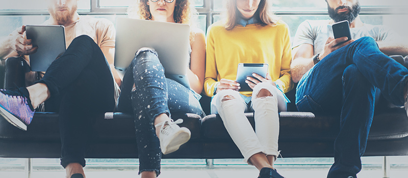 People sitting on a bench using smart devices